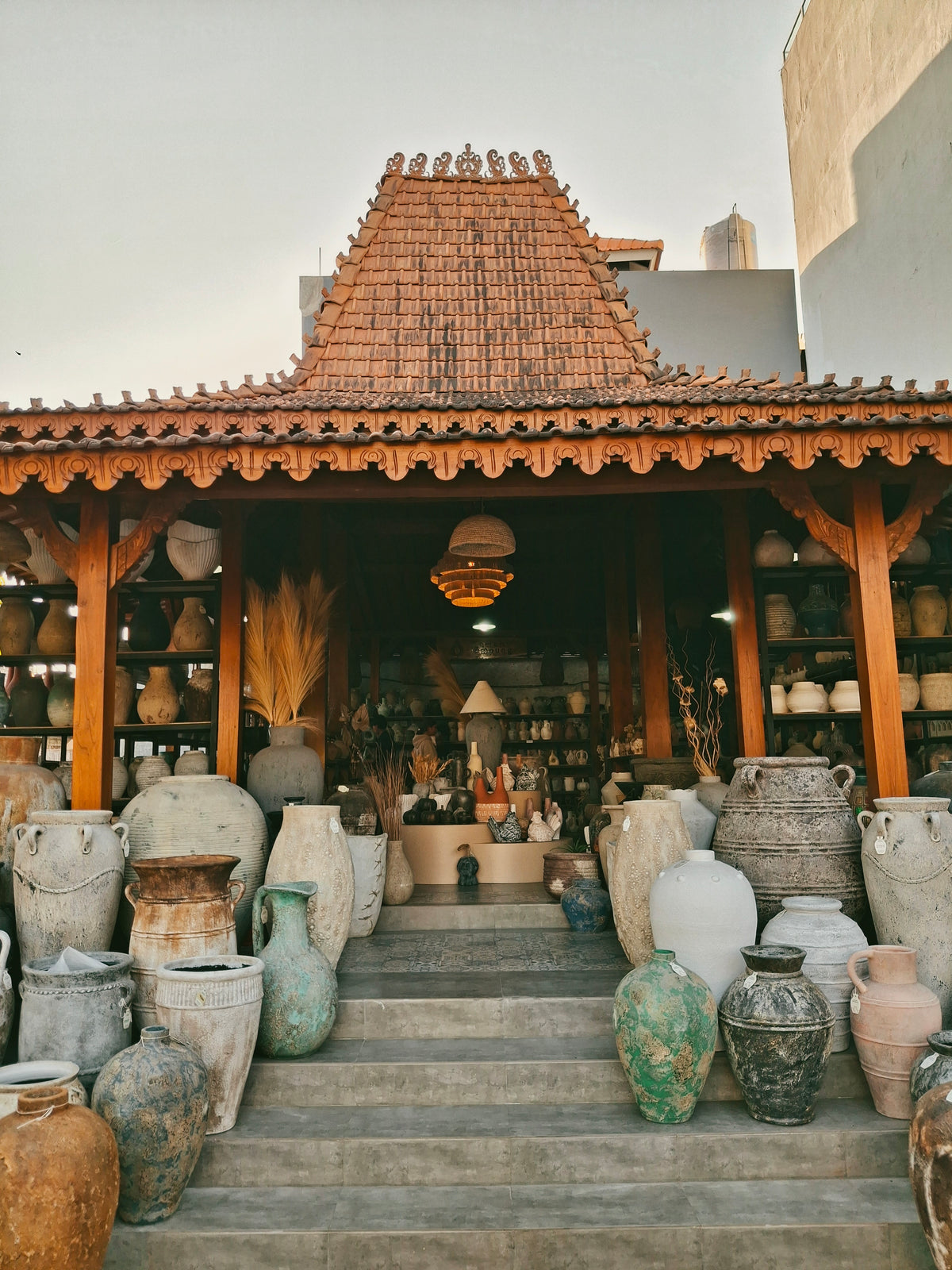 The Omah Lempung joglo showroom in Kerobokan, Bali, with terracotta pottery on its steps